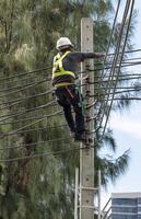 Engineer wearing helmet and safety vest climbs electric pole photo