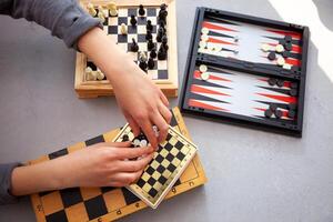 un niño obras de teatro ajedrez solo. antiguo de madera tablero de ajedrez. para niños manos. ajedrez piezas en un tablero de ajedrez. foto