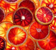 Red oranges fruit background. Sliced juicy orange. Food. Summer concept. Close-up on the light. Translucent photo