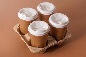 Paper cups in a cup holder for takeaway coffee. Paper cup with a drink. Disposable tableware. Eco cardboard recyclable. Brown background. Copy space photo