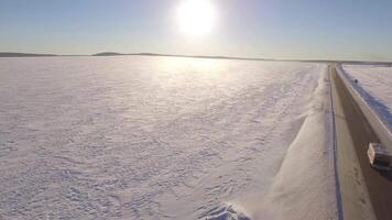 Aerial Roadways. Suv driving in white snowy evergreen forest on slippery asphalt road. Aerial view of the road and the fields in the winter video