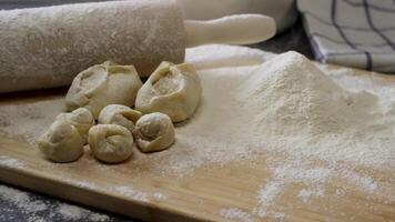 Wooden Board with rolling pin, flour, dumplings and cakes. Preparation of dough. Scene. Ingredients For the dough and a rolling pin. video