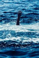 Drowning man in sea asking for help with raised arms photo