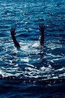 Drowning man in sea asking for help with raised arms photo