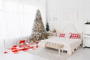 White red bedroom with a large bed and a Christmas tree by the window with gifts in a cozy house photo