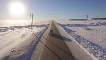 antenne wegen. suv het rijden in wit besneeuwd groenblijvend Woud Aan glad asfalt weg. antenne visie van de weg en de velden in de winter video