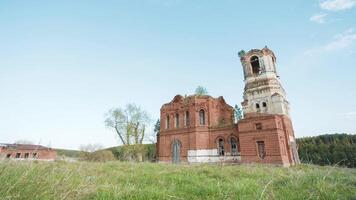 Beautiful scenic view of ancient Buddhist Temple at the background of field. Video. Ancient ruined Russian church or temple overgrown with grass among field video