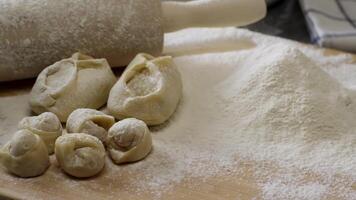 Wooden Board with rolling pin, flour, dumplings and cakes. Preparation of dough. Scene. Ingredients For the dough and a rolling pin. video