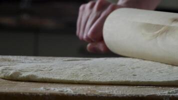 homme roulant en dehors pâte sur cuisine tableau, proche en haut. scène. le cuisinier Rouleaux une pièce de pâte sur le cuisine table avec une roulant broche. proche en haut voir. concept de cuisine et fait maison repas video