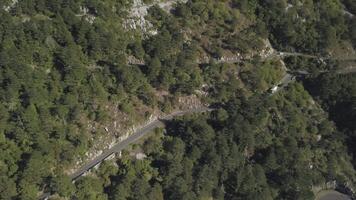 antenn se av berg serpentin väg med lastbilar och bilar. stock. väg trafik serpentin i hög bergen tajt hörn bil vänder grön skog video