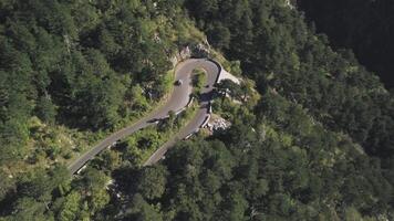 vôo acima motocicleta e uma carro em passeio dirigindo através ondulado estrada em linda exuberante arborizado montanha declive dentro verão. estoque. montanha estrada, aéreo Visão video