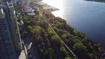 Fracht Zug mit Kohle auf Wicklung zweiseitig Eisenbahnen in der Nähe von Fluss beim Sommer- sonnig Tag, Antenne oben Sicht. Clip. Aussicht auf Fracht Zug Fahrten auf das Spuren in der Nähe von Wald. Eisenbahn Wagen. Transport video