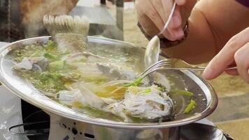 Steamed fish with lime pepper and various food ingredients on a table with Thai food dishes. Eating process. High quality 4k footage video