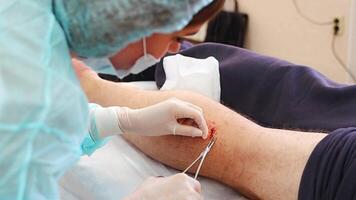 Portrait of dermatologist surgeon stitching up a wound after surgery, operation process. High quality photo video