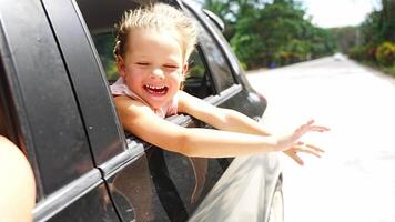 Little girl peeking out of window of the car during traveling, family trips by car with children concept. High quality 4k footage video