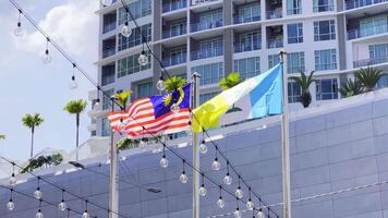 Slow motion Malaysia and Penang flags waving together on city architecture background. High quality 4k footage video