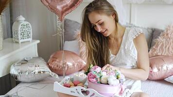 Beautiful young girl at home on the bed in the morning enjoy valentines day celebration with heart shaped balloons. High quality 4k footage video