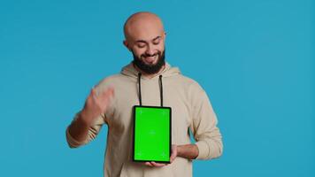 Muslim person holding tablet with greenscreen template, presenting isolated copyspace on device display. Middle eastern guy using gadget to create commercial ad with chromakey. Camera 1. video