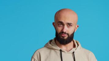 Arab person showing negative sign with fingers, expressing his refusal in front of camera. Middle eastern guy does no symbol in studio, presenting rejection and restriction gesture. Camera 2. video