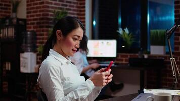 Financial analyst looking at text messages on smartphone, taking break from work with business charts, close up. Panning shot of ecommerce consultant using mobile phone to browse internet in office video