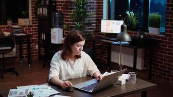 Businesswoman working overtime for company project, doing tasks in office overnight. Employee looking over accounting figures on laptop screen late at night, inputting data video