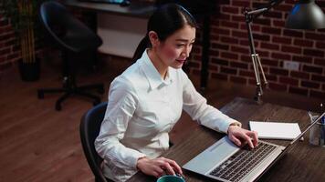 employé profiter tasse de café tandis que en cours d'analyse Ventes rapports à plan affaires développement. Bureau employé en buvant chaud boisson tandis que en utilisant portable à faire projet recherche video