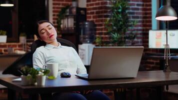 slaperig werknemer in slaap Aan computer bureau Bij nacht in steen muur kantoor, plotseling ontwaken omhoog. moe zakenvrouw op zoek Bij horloge, geërgerd door tijd voorbijgaan te langzaam terwijl werken 's nachts, camera b video