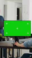 Vertical video Employee using computer at desk, monitor running greenscreen template in business agency office. Company specialist looking at isolated chromakey display with mockup copyspace, digital network.