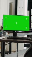 Vertical video Office desktop pc running greenscreen at empty business workstation, digital marketing agency. Startup space showing monitor with chromakey isolated template, blank copyspace screen.