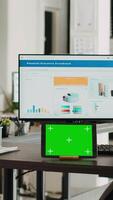 verticale vidéo bureau avec tablette montrant écran vert, vide poste de travail dans Créatif agence cotravail espace. moderne gadget fonctionnement isolé chromakey afficher dans petit affaires lieu de travail, maquette filtrer. video