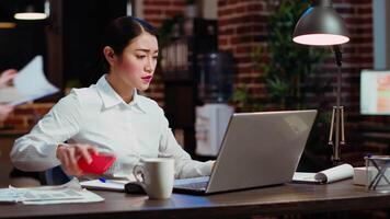 Company secretary taking phone call at office desk, answering customer inquiries while working on laptop, multitasking. Stressed worker having conversation on telephone and crosschecking data video