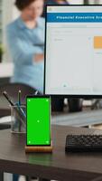 vertical vídeo vacío oficina puesto de trabajo con pantalla verde corriendo en teléfono inteligente mostrar, personas trabajando en negocio operaciones en agencia lugar de trabajo. escritorio con computadora y móvil teléfono demostración aislado espacio de copia. video