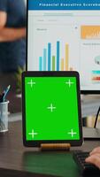 vertikal video kontor chef arbetssätt med grönskärm på läsplatta, ser på isolerat attrapp layout på enhet och efterbehandling företag operationer på dator. affärskvinna analyser tom copyspace.