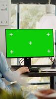 Vertical video Business manager working at monitor showing blank greenscreen template, sitting at office workstation during program. Analyst using desktop monitor with isolated chromakey copyspace layout.