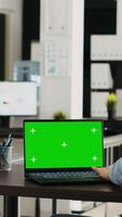 Vertikale Video Geschäftsfrau sieht aus beim grüner Bildschirm auf Laptop, Überprüfung pc beim Schreibtisch und Arbeiten auf Anfang Operationen. Mitarbeiter mit isoliert Chromakey Vorlage auf Computer, Copyspace Anzeige.