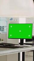 Vertikale Video leeren Schreibtisch mit grüner Bildschirm Layout auf Computer im Coworking Raum mit Menschen lösen Geschäft Operationen. Arbeitsplatz zeigen Computer mit isoliert Copyspace Attrappe, Lehrmodell, Simulation Anzeige.