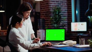 affärskvinna forska för företag projekt, ser på dokument på grön skärm bärbar dator. medarbetare ser över bokföring siffror på krom nyckel elektronisk enhet visa i kontor video