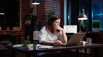 cansado contador luchando a permanecer despierto a espacio de trabajo escritorio mientras ingresando datos en computadora portátil, panorámica disparo. cerca arriba de agotado mujer de negocios bostezando en oficina mientras trabajando durante la noche, cámara un video