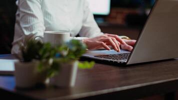 Close up shot of asian businesswoman researching key data for company project, doing tasks overnight. Office clerk looking over accounting figures on laptop screen late at night, typing on keyboard video