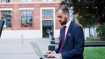 Young businessman working on the laptop in a business district, close up slow motion. Business on the go video