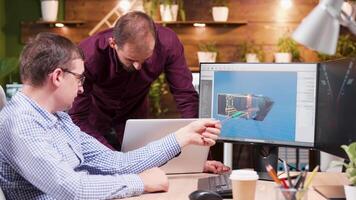 Graphic designer in game industry sitting at his office showing his assistant new gaming graphics. video