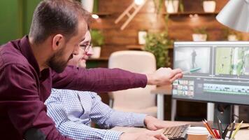 Two male colleagues debating over a new video project they are working on in cozy modern office