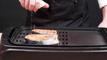 Cook seasoning a fillet of tasty salmon with lemon juice. Piece of salmon frying on frying pan. video