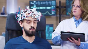 männlich geduldig mit Augen geschlossen während Arzt Überprüfung Gehirn Aktivität. Neurowissenschaften Einrichtung. video