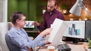 Architect in the office talking about the engineering for the new building structure with his assistant. video