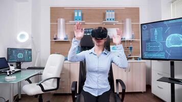 hembra científico en un investigación laboratorio utilizando virtual realidad gafas de protección. hembra investigador en un cerebro clínica. video