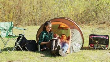 copain pose vers le bas sur camping tente tandis que petite amie en train de lire une livre. video