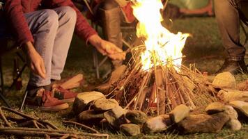 Handheld Aufnahmen von Mann Herstellung Lager Feuer zum seine freunde im ein kalt Nacht. video