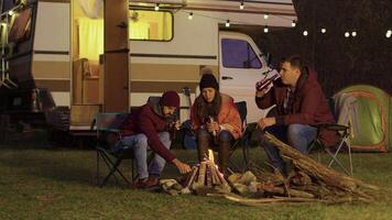 amigo de un Pareja Ayudar a ligero el acampar fuego. retro camper camioneta. ligero bombillas en el antecedentes. video