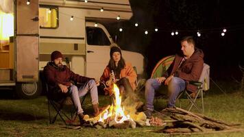 grupo de amigos disfrutando un tranquilo momento en frente de el fuego en un acampar a noche video
